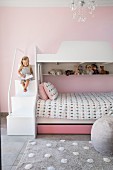Girl sitting on steps of bunk beds in pink children's bedroom
