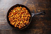 Roasted wild forest mushrooms chanterelle in pan on wooden background