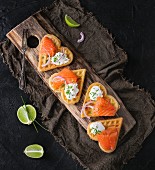 Wafers as heart shape with salted salmon, red onion, chive, lime and ricotta cheese on wooden cutting board