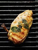 A chicken breast with herbs on a barbecue