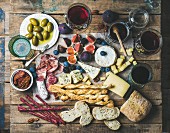 Various wines in glasses, meat variety, bread, sun-dried tomatoes, honey, green olives, figs, nuts and berries