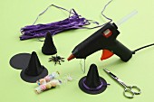 Craft utensils for Halloween decorations: glue gun, hand-made witches' hats, sweets and rubber spider