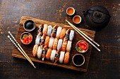 A Nigiri sushi set for two on a wooden serving board with chopsticks and green tea