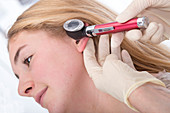 Girl having ear examined with otoscope