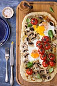 Breakfast pizza with eggs, mushrooms and cherry tomatoes