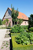 Square flowerbeds edged with box hedges outside house