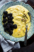 Homemade mango yoghurt with blackberries and pistachios
