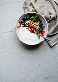 Joghurt mit frischen Beeren und Granola in einem Schälchen