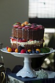 A vanilla cake decorated with fresh fruit on a cake stand