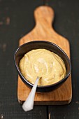 Mustard sauce in a bowl on a chopping board