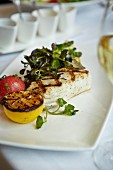 Grilled halibut with lemon and cress on a restaurant table