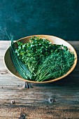 Chives, parsley and dill in a wooden bowl