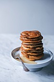 A stack of vegan banana pancakes drizzled with maple syrup