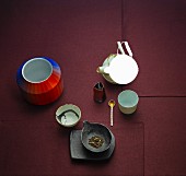 Geschirr und Teeutensilien auf rotem Untergrund