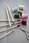 Different colours of thread wrapped around ends of wooden skewers
