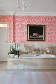 Pink floral wallpaper above bathtub in bathroom