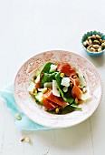 A salad with spinach, apples, serrano ham, almonds and pistachios