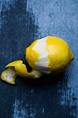 A partially peeled fresh lemon on a wooden surface