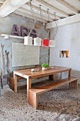Simple, exotic-wood table and benches below designer lamps