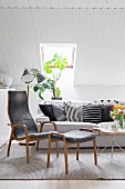 Sofa und Relaxstuhl mit Fussschemel in Grautönen unter Dachschräge in skandinavischem Wohnzimmer
