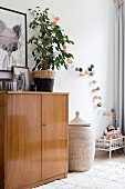 Retro sideboard, house plant and dolls' bed in corner of nursery
