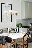 Round white table, bentwood chairs and retro lamp next to kitchen counter