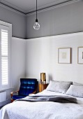 Schlafzimmerecke mit blauem Retrosessel und weiß-grauer Wand