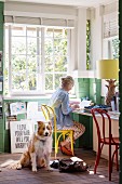 Woman on laptop in bright home office with dog