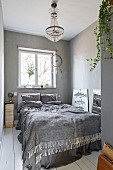 Schlafzimmer in Grautönen mit weißem Dielenboden, Kronleuchter und Traumfänger