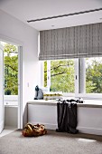Upholstered bench in front of the window with a striped roller blind