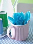 Blue plastic spoons in pink milk jug