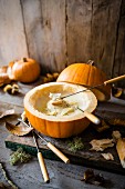 Cheese fondue served inside a hollow pumpkin with bread and autumnal leaves