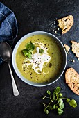 A bowl of pea and watercress soup with sour cream and bread