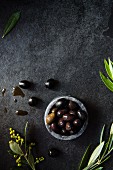 A bowl of olives with olive leaves
