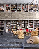 Offener Wohnraum mit Bücherwand in einem Haus aus Beton