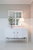 Old sideboard against wainscoting and below interior window