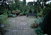 Runde Terrasse mit Natursteinen gepflastert, Kübel mit Kräutern