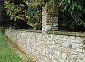Kunstvoll gestaltete Steinmauer aus Kieselsteinen