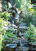 Waterfall with natural stones between ferns is animated by elves