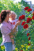 Junge Frau und Tochter freuen sich über Rosenblüten