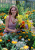 Young woman picking flowers bouquet from the cottage garden