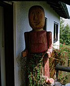 Carved wooden doll at the house entrance