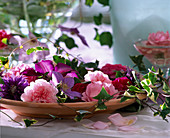 Bowl with rose blossoms, clematis blossoms and ivy