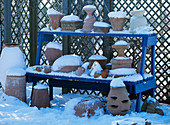 Winterfeste Terrakottatöpfe auf einer Etagere mit Schnee