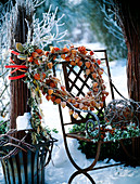 Iron chair decorated with hoarfrost with wreath of physalis (lampion flower), willow ball