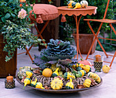 Iron bowl with willow wreath, ornamental pumpkins, brassica (ornamental cabbage)