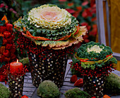 Brassica (ornamental cabbage) in mosaic pots, pink rosehip wreaths, colourful raffia, moss