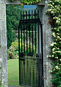 Open, wrought-iron garden gate leading into the garden