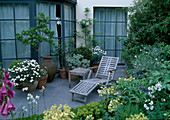 Terrace with Convolvulus cneorum (silver bindweed), Nerium (oleander), Argyranthemum (daisy), wooden lounger, side table