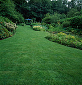 Gartenansicht mit Rasen, Rhododendron, Staudenbeeten und Teich, im Hintergrund blauer Pavillon